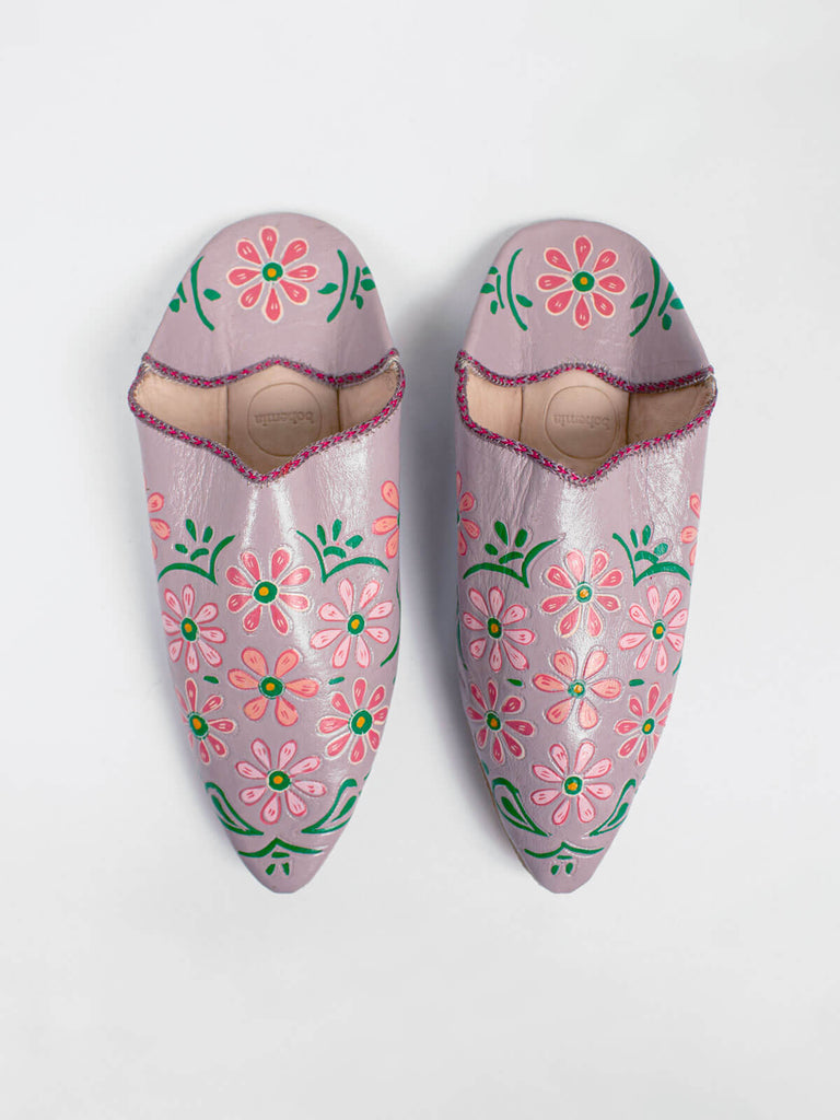 A pair of pointed babouche slippers in a dusky lilac leather with colourful hand painted blooms, in pink and green