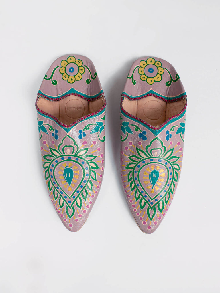 A pair of pointed babouche slippers In a dusky lilac leather with exquisite hand painted, nature inspired elements and golden highlights