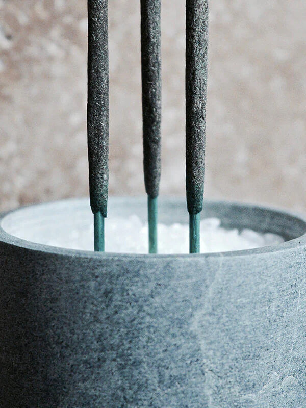 Three sticks of incense in a grey stone holder