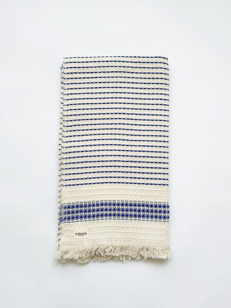 Beautifully tactile Turskich cotton hammam towel with a subtle blue stripe and hand-tied tassel fringe, featuring a waffle texture weave | Bohemia Design