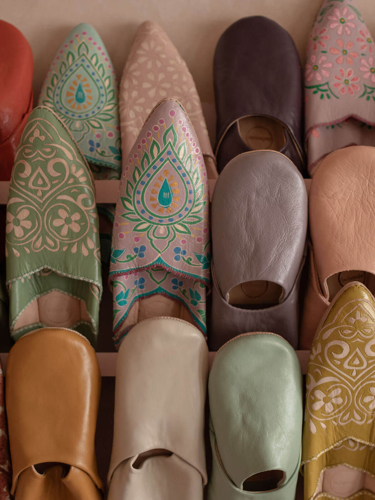 A display of different styles of Bohemia Moroccan slippers including basic babouche slippers in plum