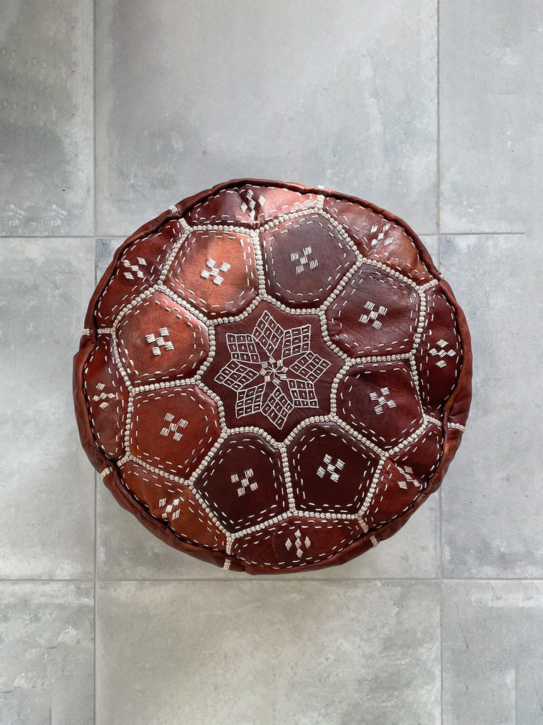 Brown leather Moroccan pouffe with a decorative hand embroidered tile pattern on the top