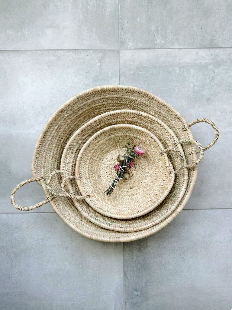 Three nesting Moroccan woven basket plates with dried flowers