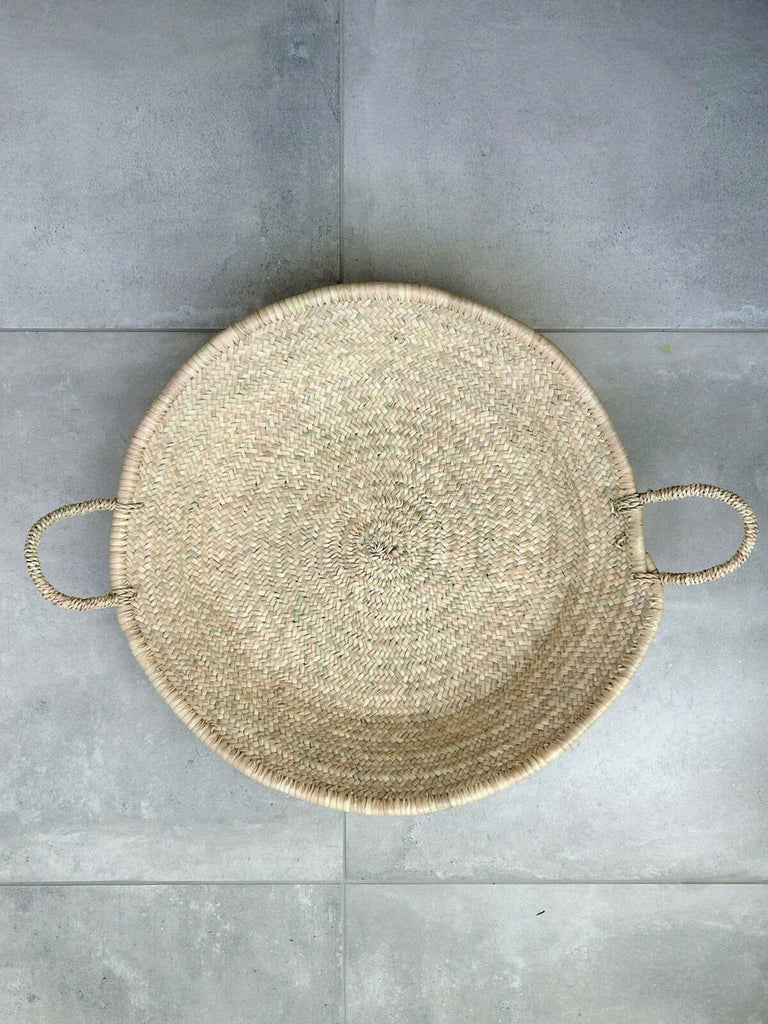 Large Moroccan woven plate by Bohemia, handcrafted from natural palm leaf fibres and featuring two short handles.