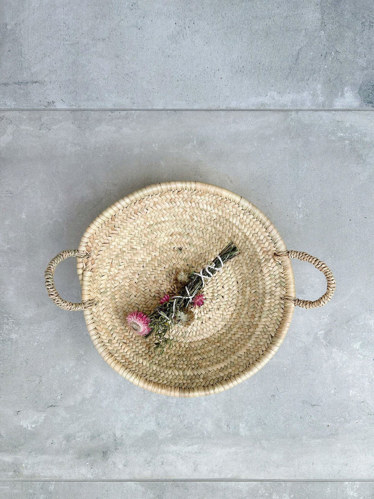 Small woven plate by Bohemia, crafted from natural palm leaf fibres holding dried flowers