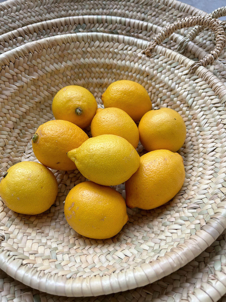 Lemons in a natural woven plate with handles, handcrafted by Moroccan artisans