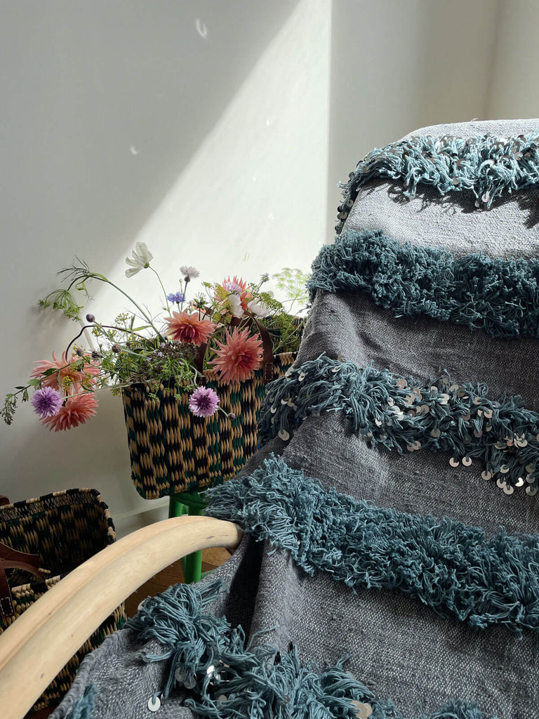 Contemporary grey blanket draped on a chair embellished with soft fringing and silver sequins