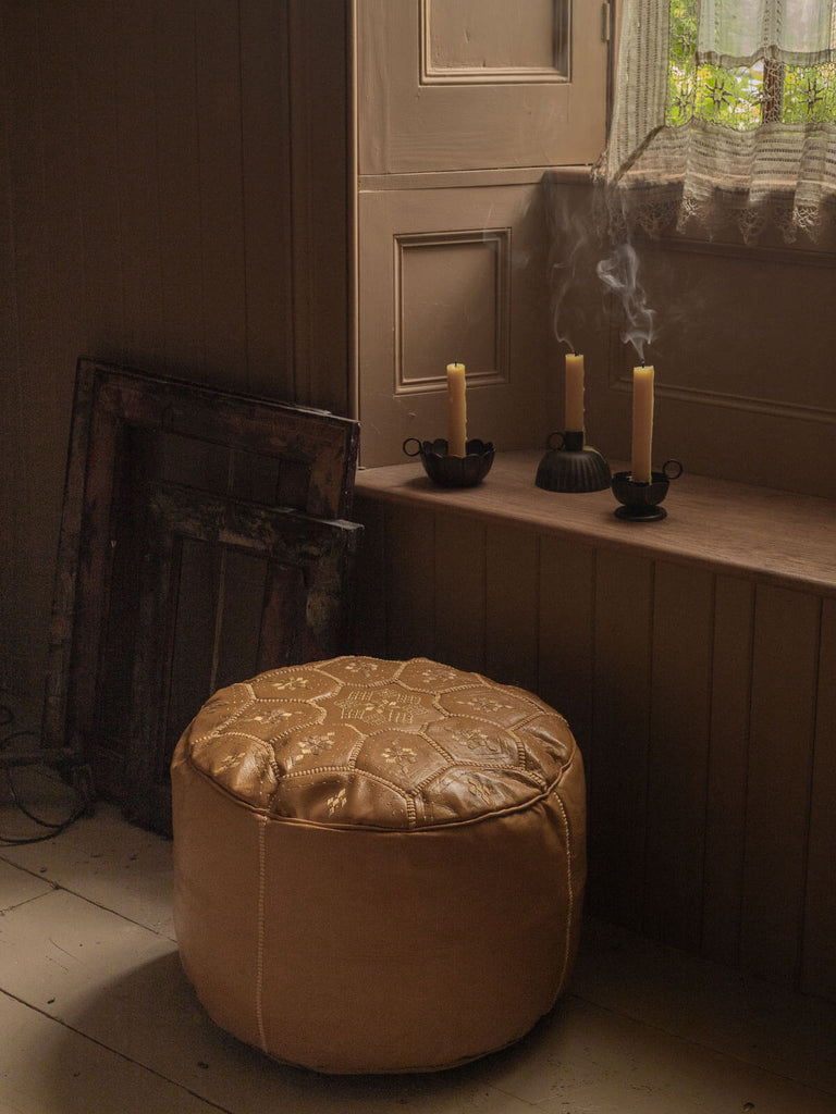 Mustard Leather Moroccan Pouffe by a window with candles