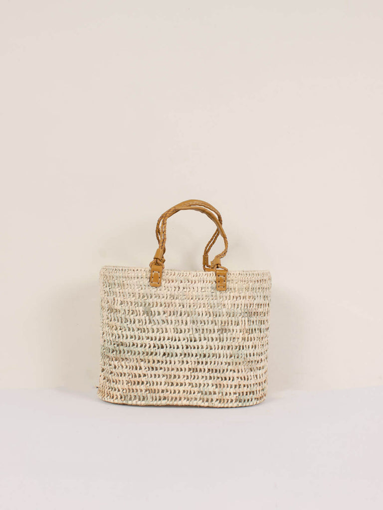 A medium open weave basket with mustard colour pleated leather handles