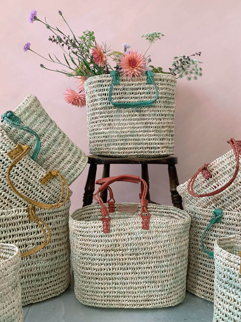 Different coloured pleated leather handle baskets surrounding one basket filled with flowers