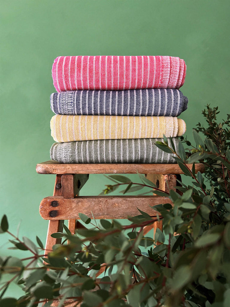 Stack of striped Portobello hammam towels in bright summer colours on a wooden stool | Bohemia Design