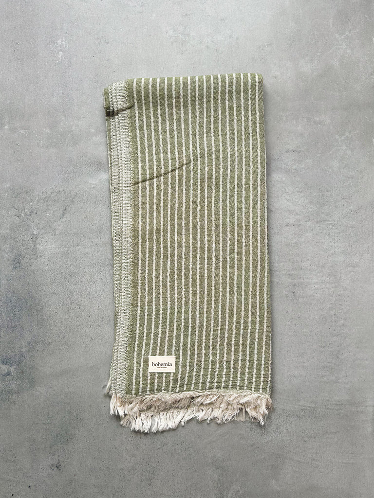 Soft Portobello hammam towel in olive green stripe, set against a textured grey background by Bohemia Design