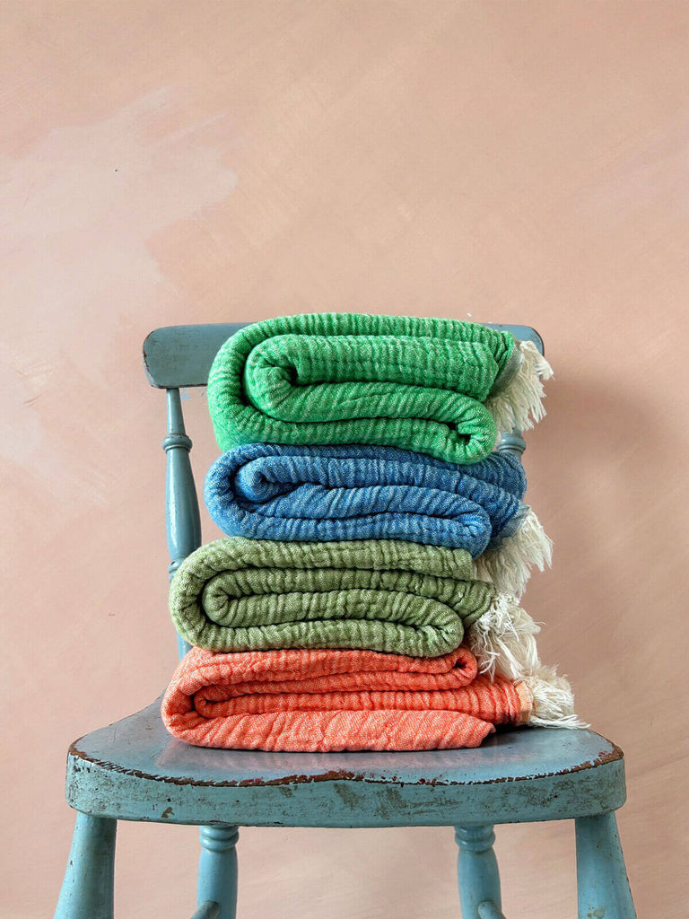 Colourful stack of vibrant, textured cotton Samos hammam towels folded on a wooden chair | Bohemia Design