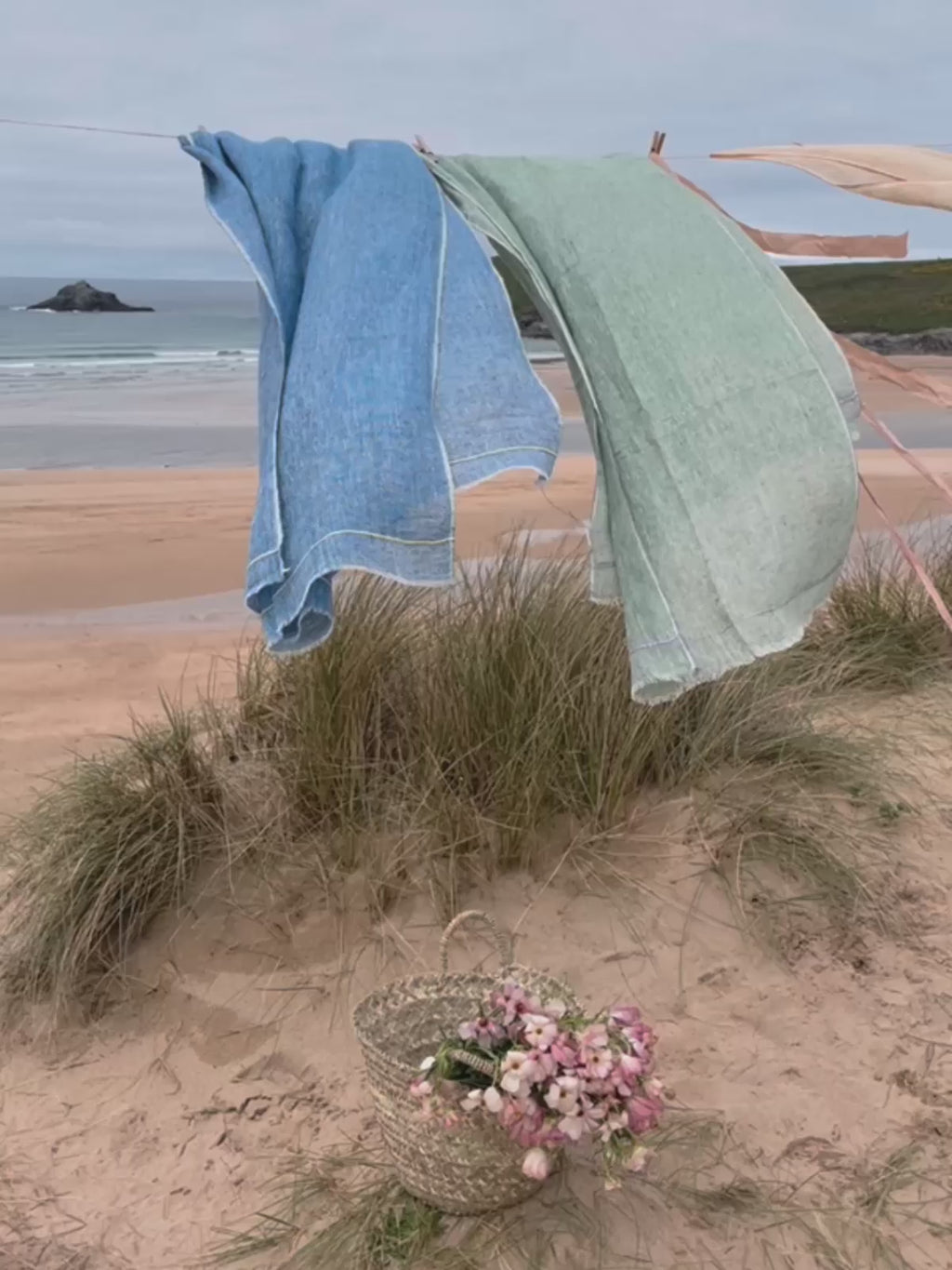 Video of linen scarves hanging on a washing line by the sea