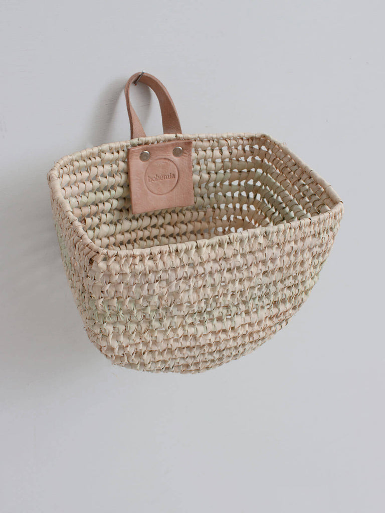 Half moon shape mini woven wall hanging storage basket with leather loop hook and natural open weave design.