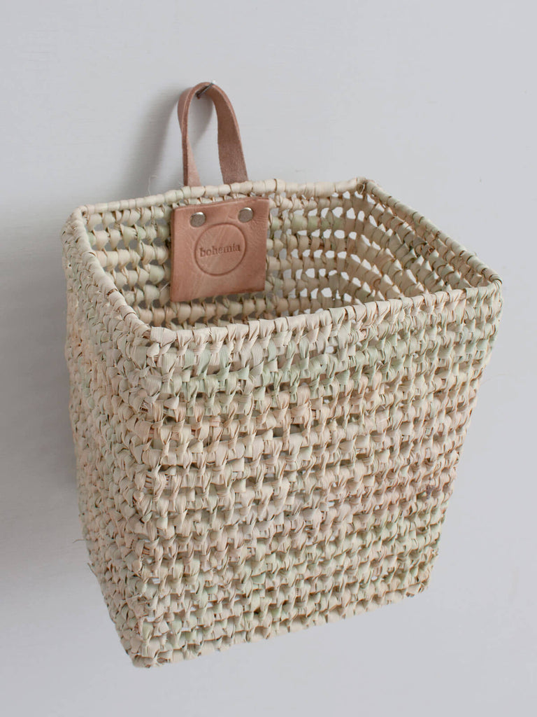 Mini woven wall hanging storage basket with leather loop hook and natural open weave design.