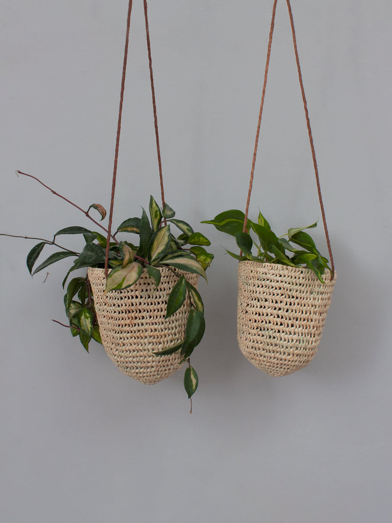 Two dome shaped natural woven indoor hanging baskets with finely braided tan leather