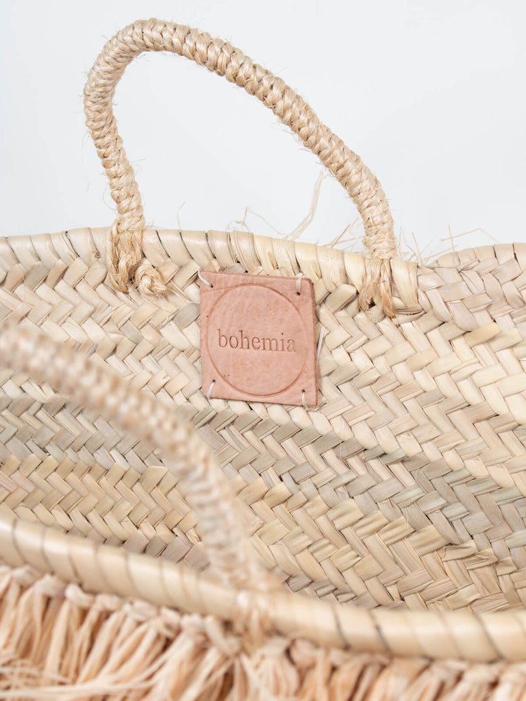 Close up of the short handled Raffia Tassel Basket with leather label inside