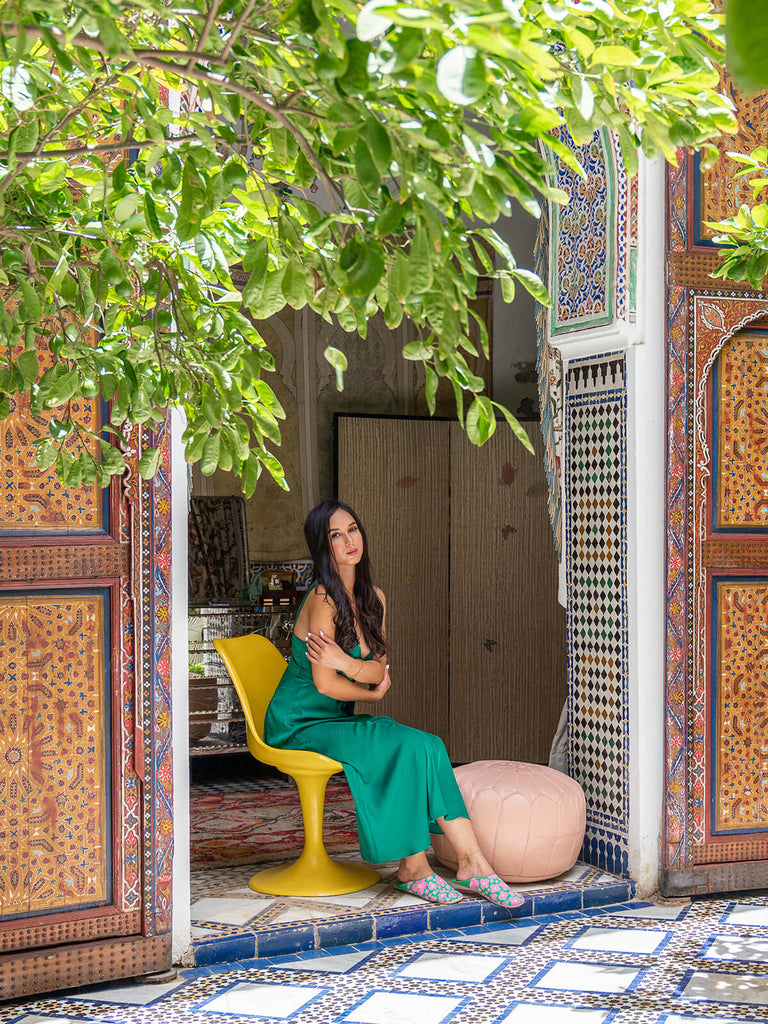 Model wearing Bohemia Design Margot babouche slippers in green floral pattern at a Moroccan riad 