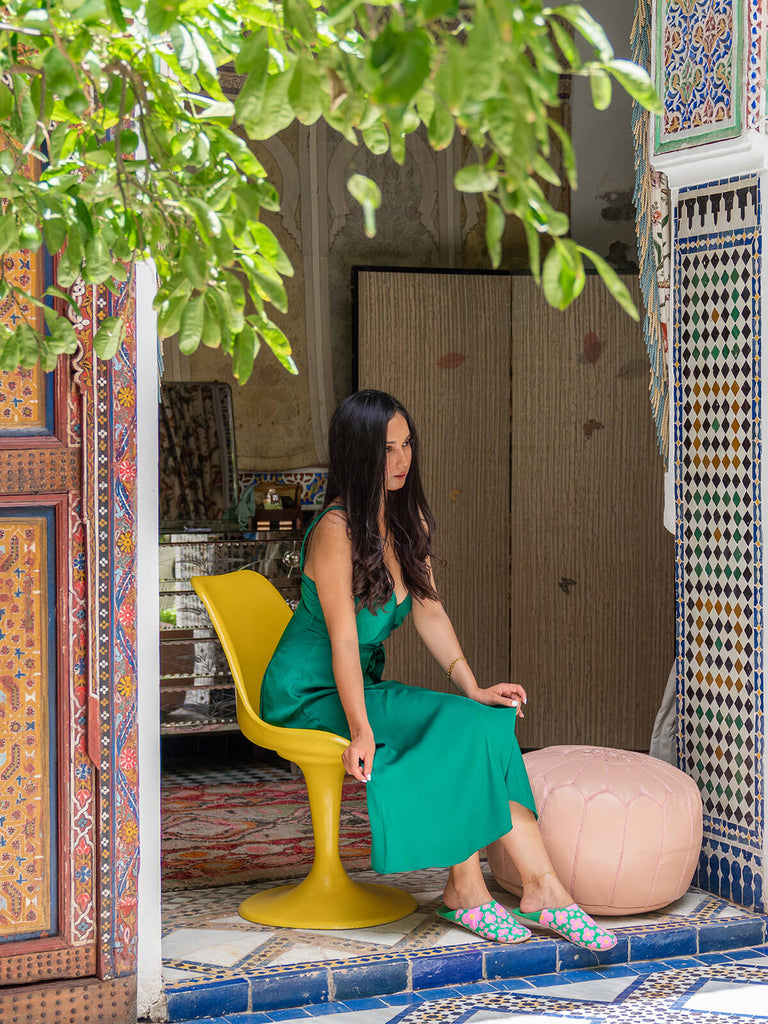 Model wearing Bohemia Design Margot babouche slippers in green floral pattern at a Moroccan riad 