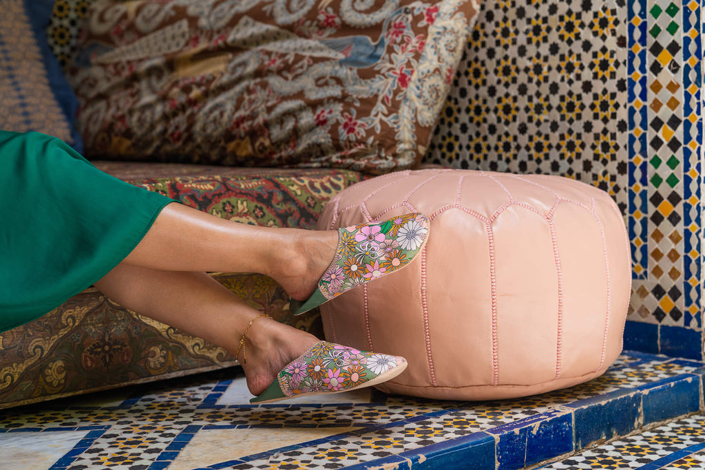 Model wearing Bohemia Design Margot babouche slippers in pink and green floral pattern at a Moroccan riad 