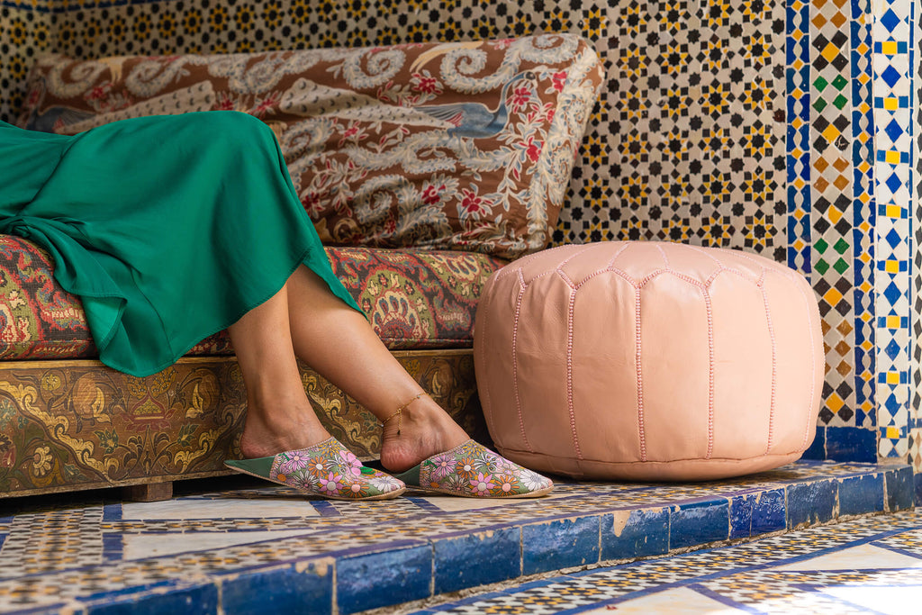 Model wearing Bohemia Design Margot babouche slippers in pink and green floral pattern at a Moroccan riad 