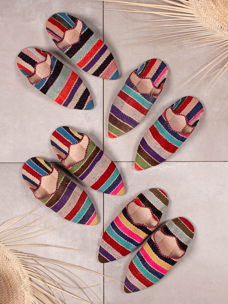 Group of Bohemia design boujad babouche slippers in multi stripe pattern on grey tiles with raffia straw hats