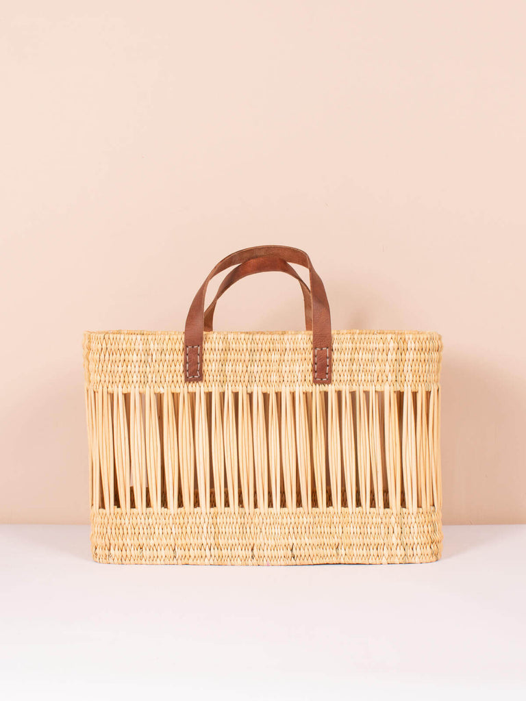 Decorative natural reed basket bag with intricate handwoven design and short leather handles