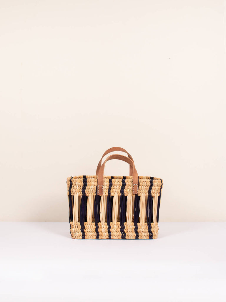 Small boxy woven reed basket bag with leather handles and stylish indigo stripe pattern