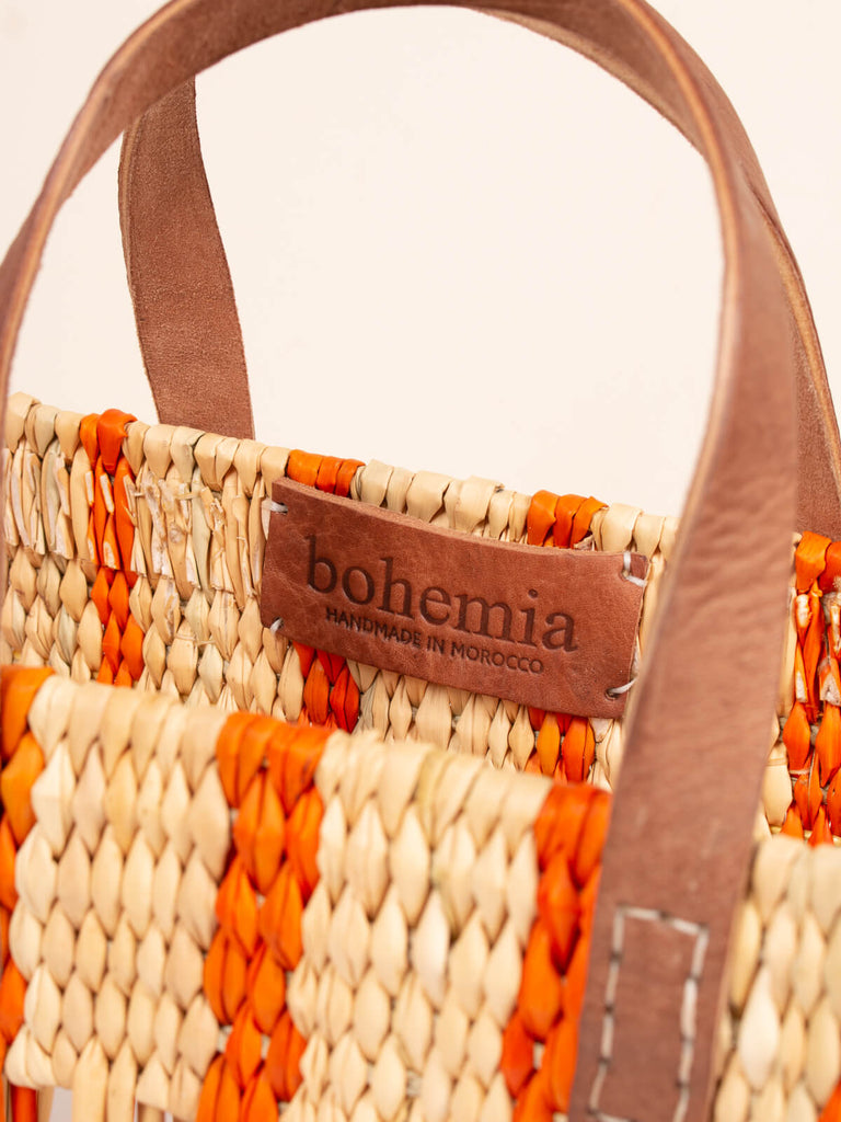 Decorative woven reed basket bag with leather handles and hand stamped Bohemia label