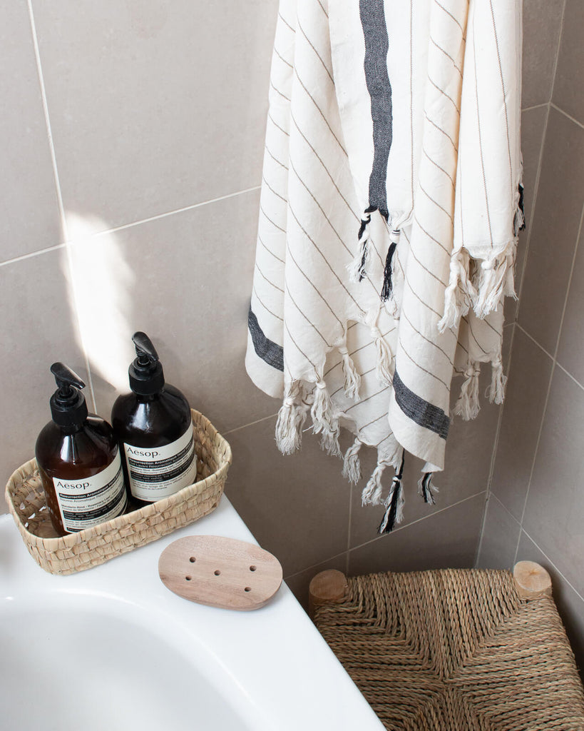 A bathroom scene featuring the walnut wood soap dish, open weave tray and hanging hammam towel