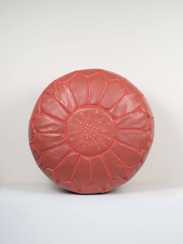 Moroccan leather pouffe in terracotta with decorative embroidery panel.