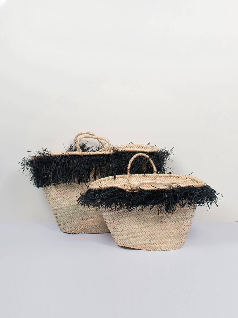 A small and medium raffia tassel basket sitting next to each other.