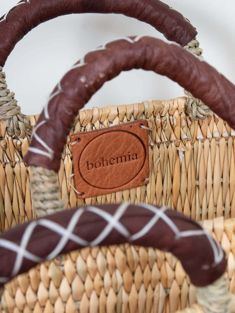 Natural leather handles and branded Bohemia leather label inside a woven reed storage basket