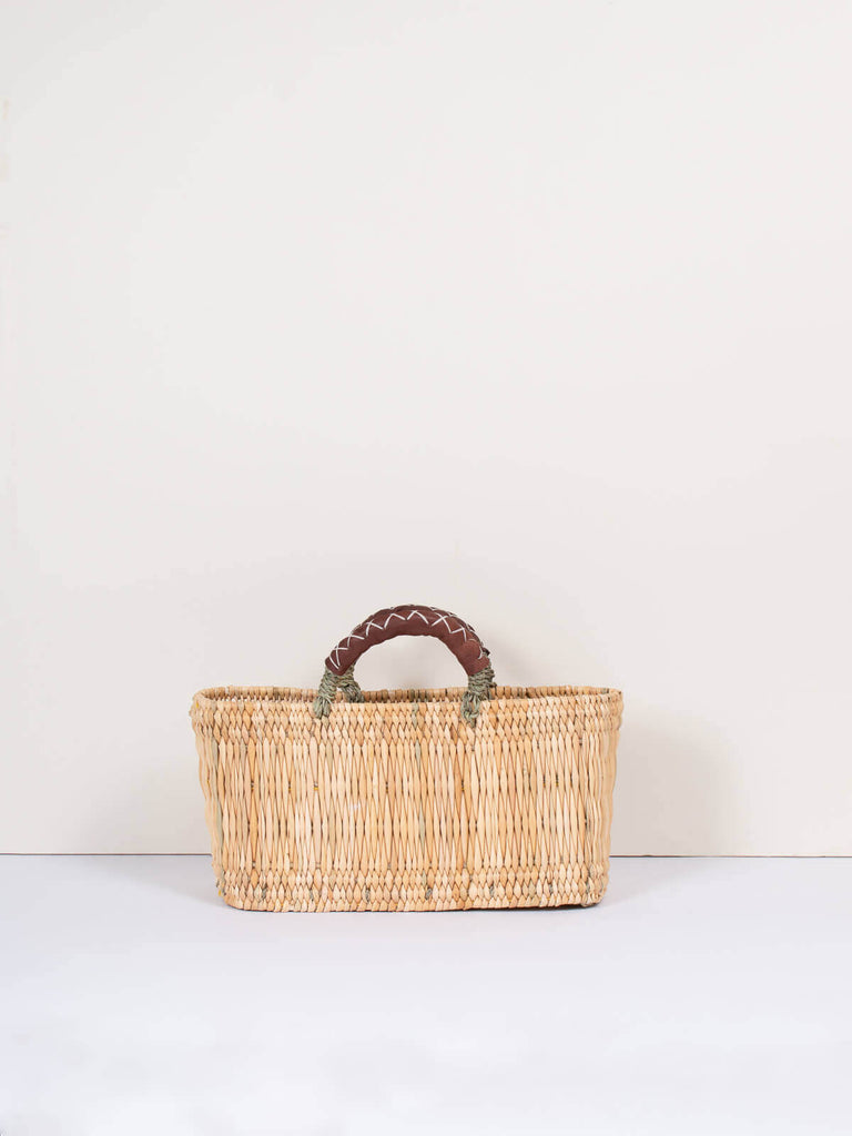 Small handwoven rectangular natural reed wicker basket with leather handles