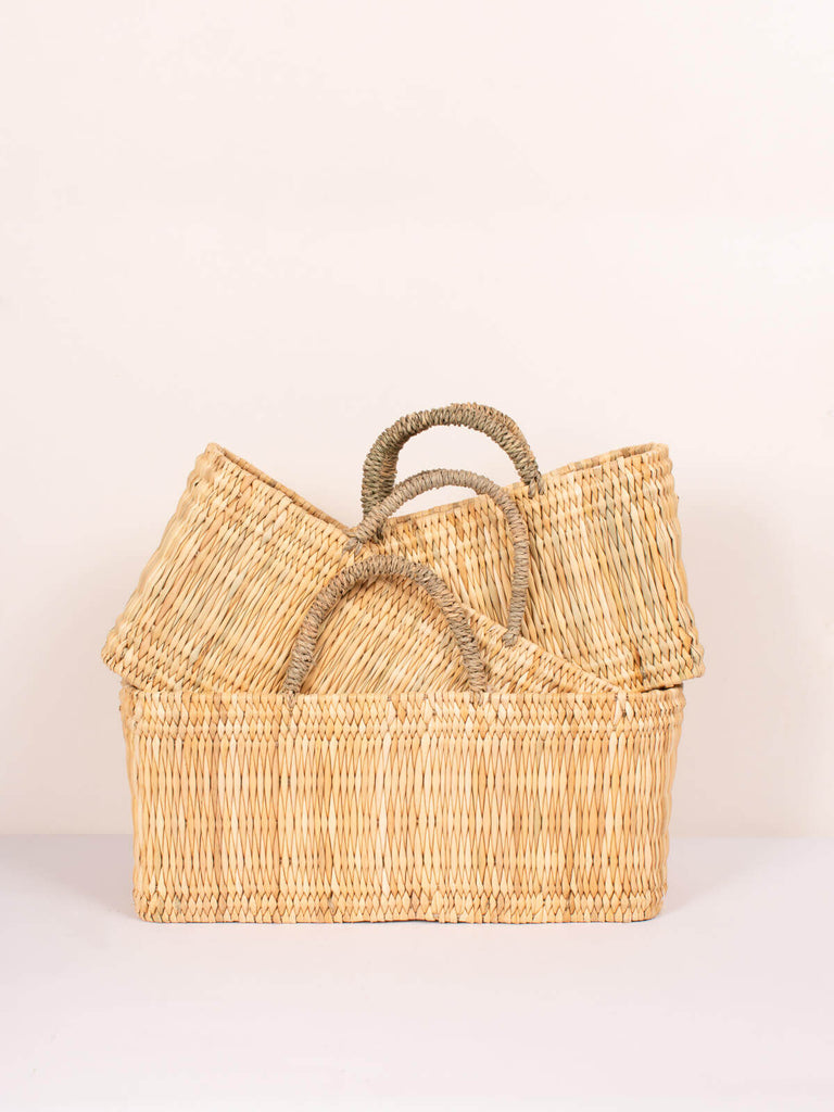 Three sizes of natural handwoven reed wicker storage baskets with sturdy handles and rectangular shape
