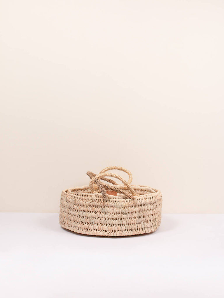 Large round open weave storage basket with handles for use as a deep tray or woven platter