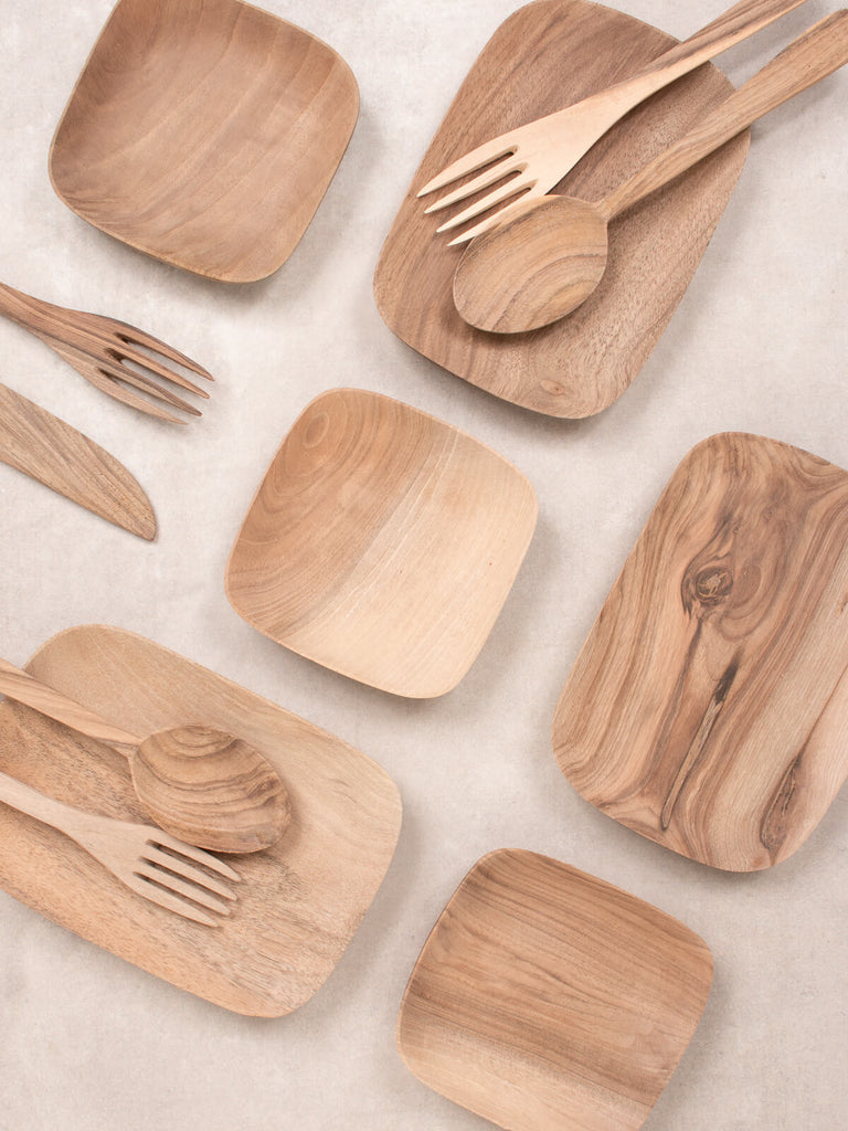 A flat lay of handcrafted walnut wood trays, forks and spoons.