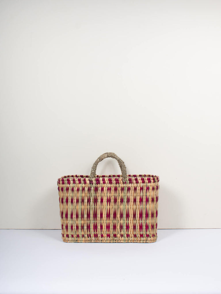 Small natural woven rectangular reed basket bag with short handles featuring a skillfully weaved violet pattern