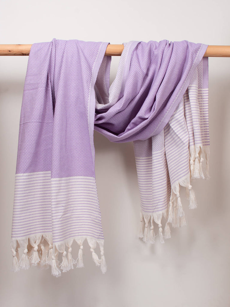 Striped Amalfi Hammam Towel in lilac stripe by Bohemia Design hanging on a wooden rod