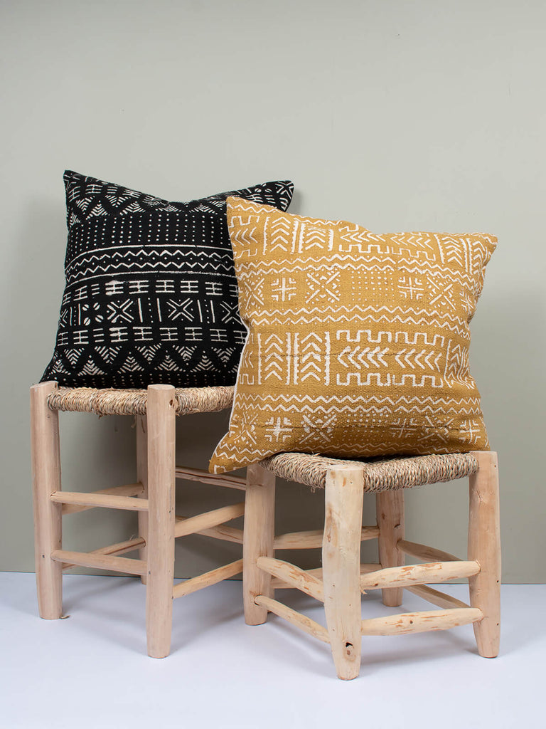 Black and saffron cushions with mudcloth patterns sitting on stools