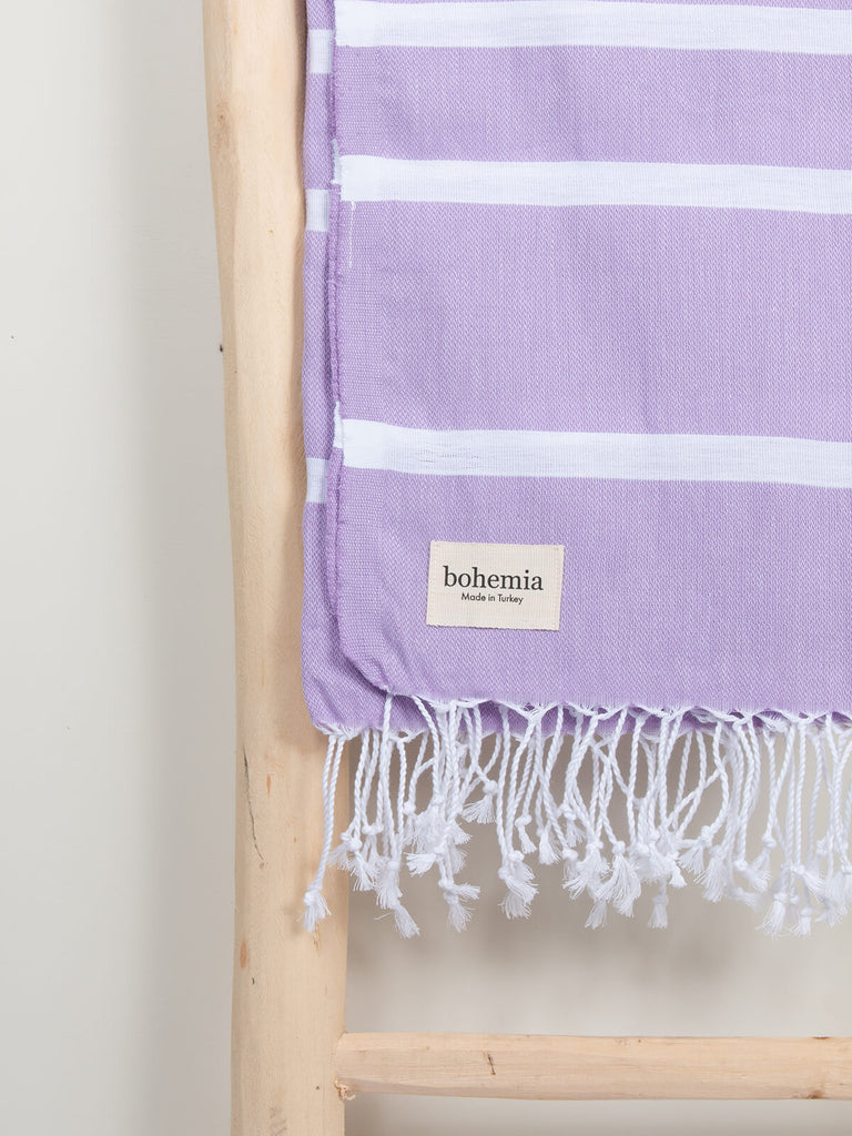 Ibiza Summer Hammam Towel in lilac stripe pattern by Bohemia Design hanging on a wooden ladder