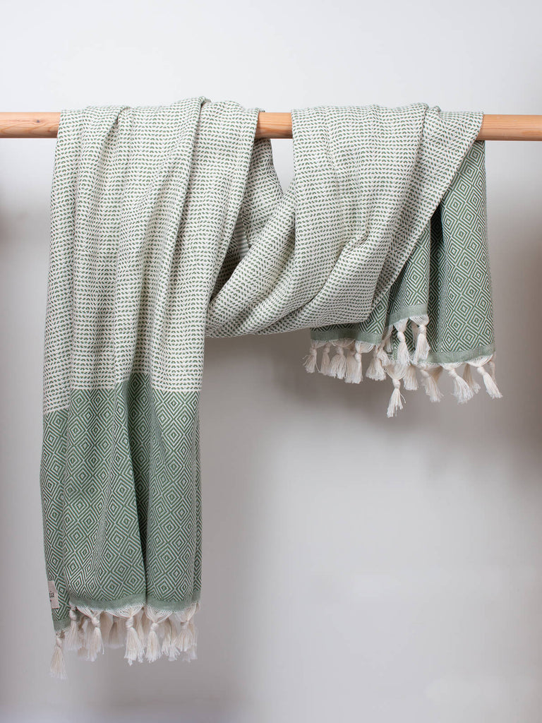 Nordic Dot Hammam Towel in olive diamond pattern by Bohemia Design hanging on a wooden rod