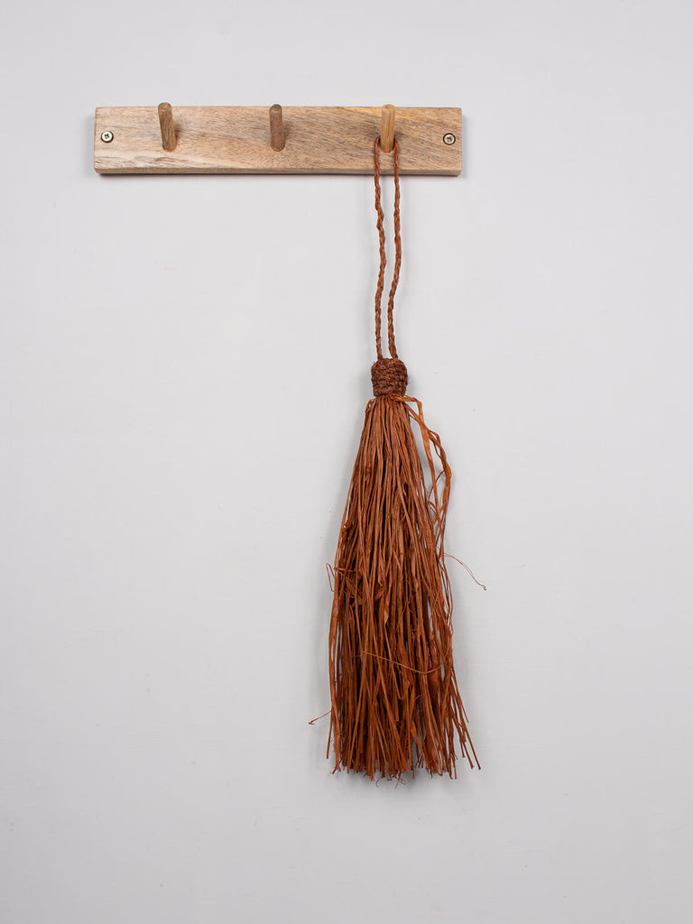 Tobacco raffia tassel hanging on a wooden hook