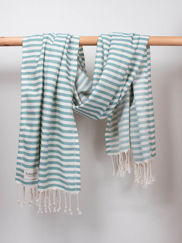Striped Sorrento Hammam Towel in grey green stripe by Bohemia Design hanging from a wooden rod
