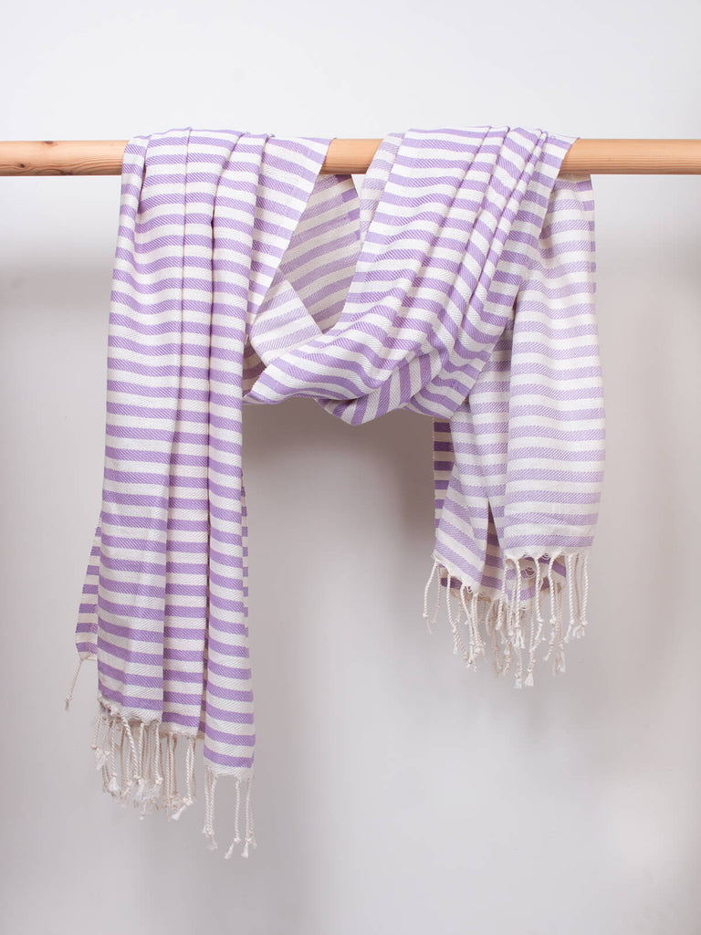 Striped Sorrento Hammam Towel in lilac stripe by Bohemia Design hanging from a wooden rod