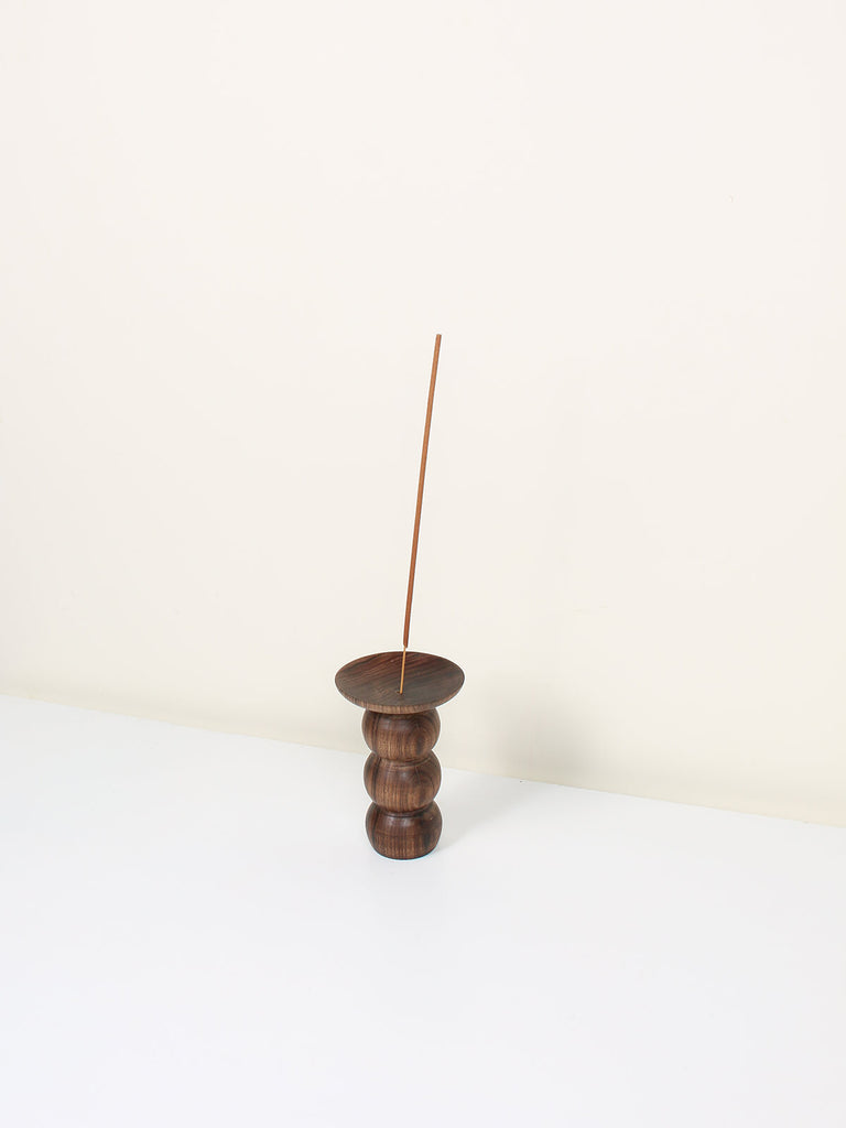 Natural walnut wood incense holder in a stacked bubble shape with a stick of incense