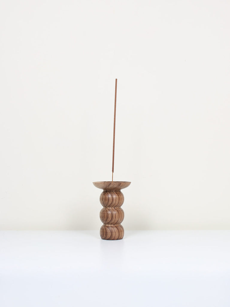 Natural walnut wood incense holder in a stacked bubble shape with a stick of incense