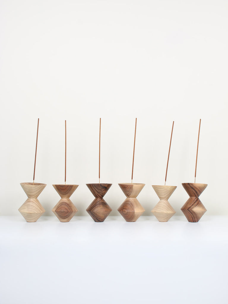A row of Natural walnut wood incense holders in a cubist shape with sticks of incense 