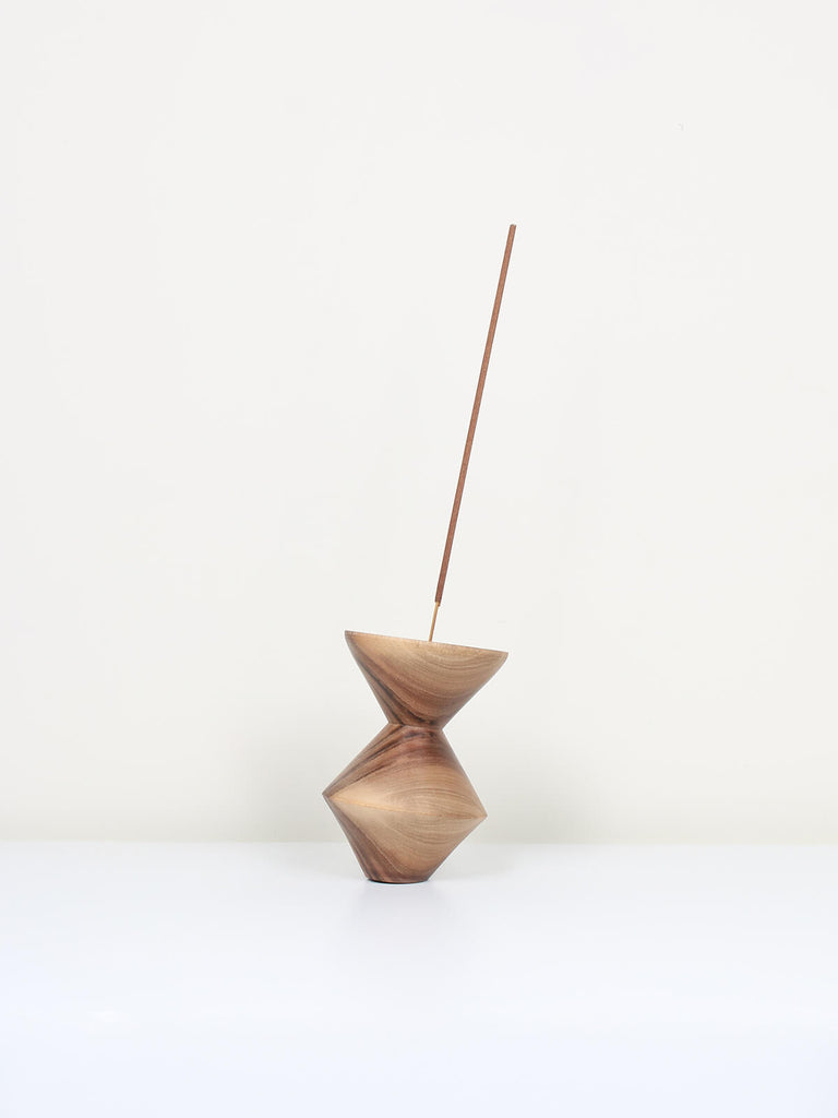 Natural walnut wood incense holder in a cubist shape with a stick of incense 